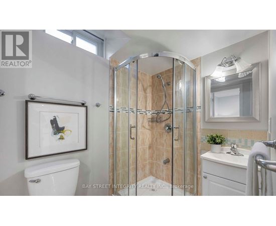 A bathroom with a white toilet, a sink, a mirror, and a shower with a glass door.