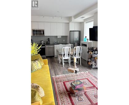 A living room with a yellow couch and a rug with a coffee table in front of it.