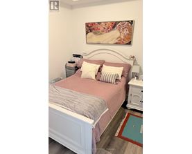 A bedroom with a bed, nightstand, and a painting on the wall.