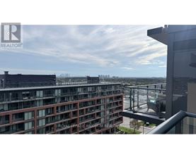 A view from a balcony of a building with a glass railing and a cityscape in the background.