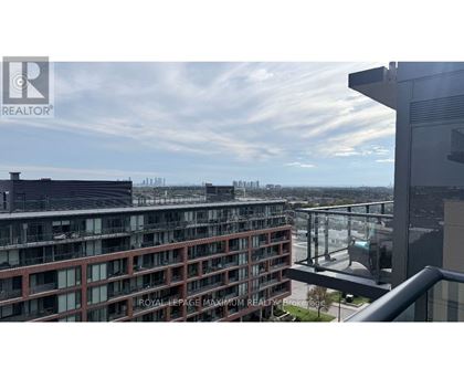 A view from a balcony of a building with a glass railing and a cityscape in the background.