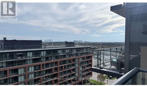A view from a balcony of a building with a glass railing and a cityscape in the background.