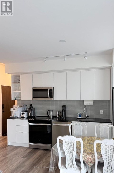 A kitchen with white cabinets and a black counter top.