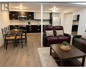 A modern kitchen and living room with dark brown leather furniture.