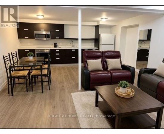 A modern kitchen and living room with dark brown leather furniture.