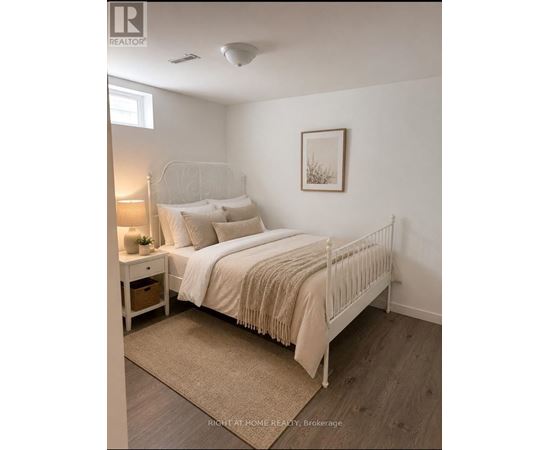 A bedroom with a white bed and a beige rug.
