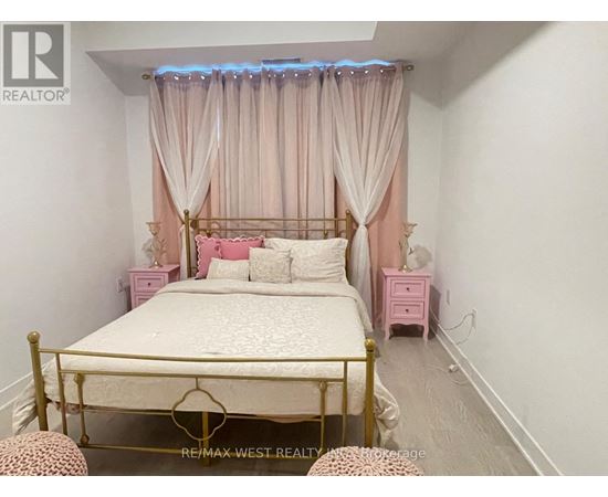 A bedroom with a bed, pink nightstands, and a canopy bed with curtains.