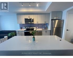 A modern kitchen with a stainless steel refrigerator and a white countertop.