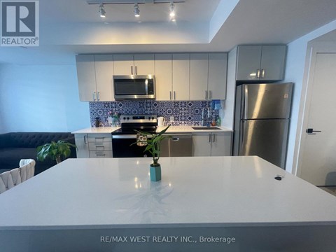 A modern kitchen with a stainless steel refrigerator and a white countertop.