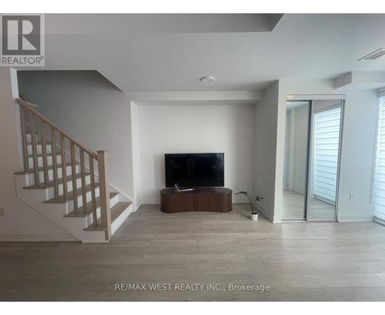 A spacious living room with a television and a staircase.