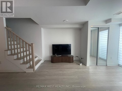 A spacious living room with a television and a staircase.