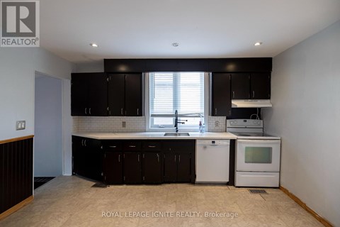 A kitchen with black cabinets and white appliances.