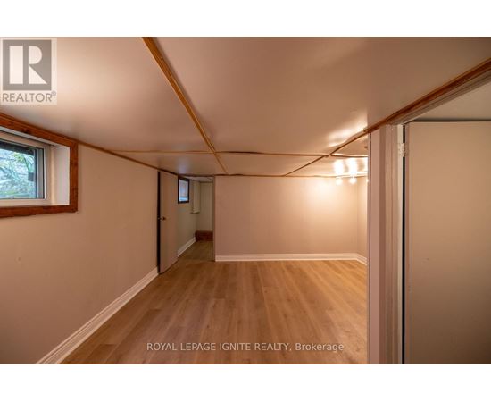 A room with wooden floors and white walls, with a window on the left side.