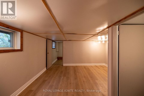 A room with wooden floors and white walls, with a window on the left side.