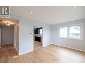A spacious room with wooden flooring and white walls.