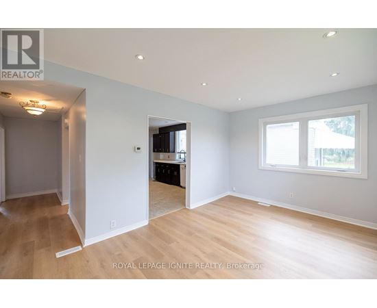 A spacious room with wooden flooring and white walls.