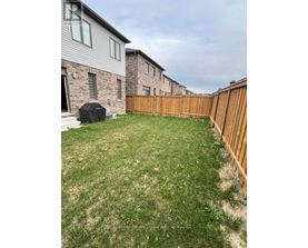 A backyard with a wooden fence and a lawn.