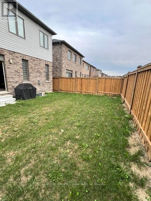 A backyard with a wooden fence and a lawn.