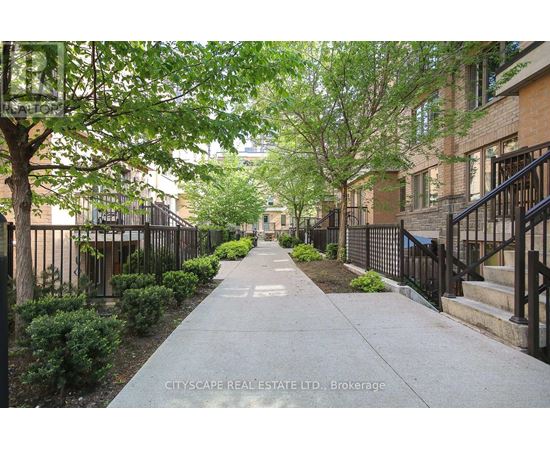 A tree-lined sidewalk in front of a brick building.