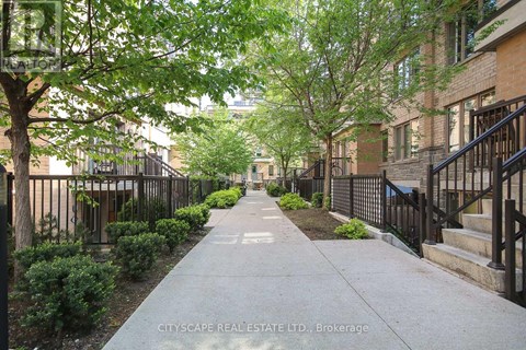 A tree-lined sidewalk in front of a brick building.