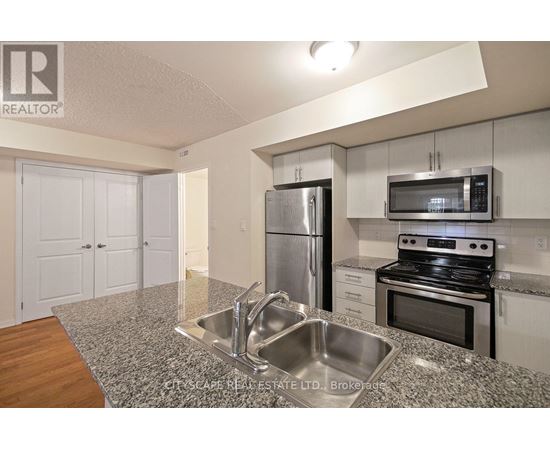 A kitchen with a stainless steel refrigerator, microwave, and oven.
