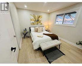 A bedroom with a bed, a bench, and a painting on the wall.