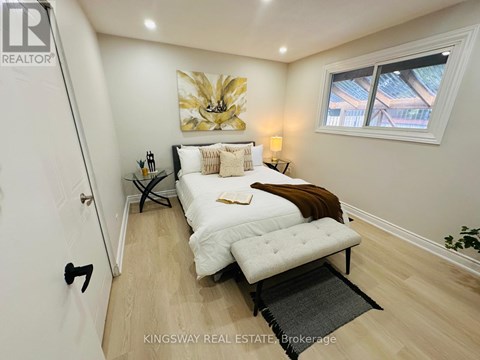 A bedroom with a bed, a bench, and a painting on the wall.