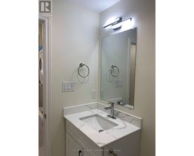 A bathroom with a sink, mirror, and light fixture.