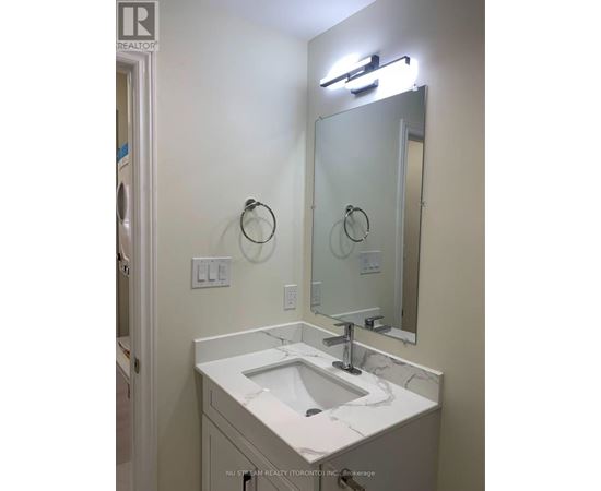 A bathroom with a sink, mirror, and light fixture.