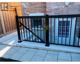 A black metal fence in front of a brick wall.