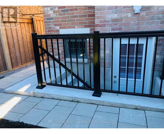 A black metal fence in front of a brick wall.