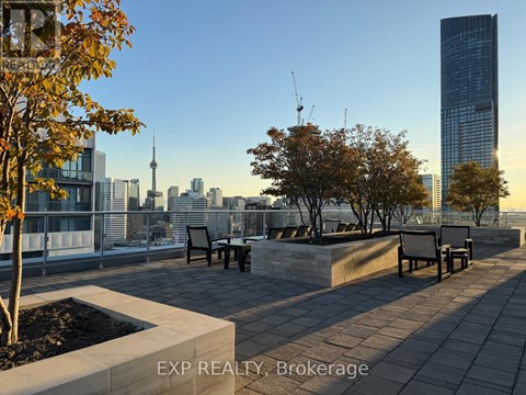 A cityscape with a tall building in the background and a park area in the foreground.