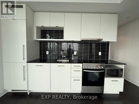 A kitchen with white cabinets and black countertops.
