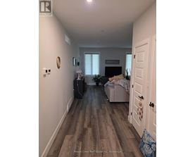 A hallway with a door on the right and a couch with a blanket on it in the background.