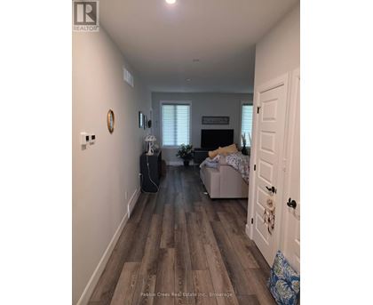 A hallway with a door on the right and a couch with a blanket on it in the background.
