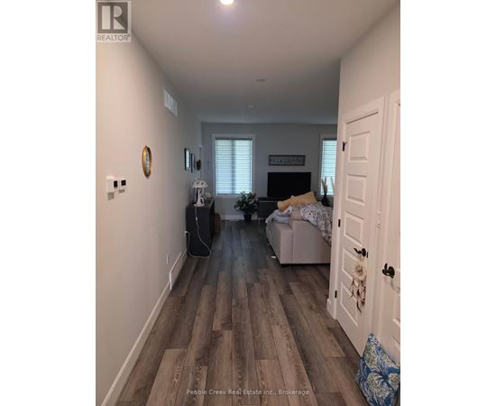 A hallway with a door on the right and a couch with a blanket on it in the background.