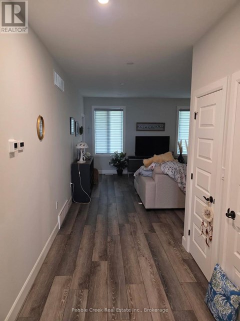 A hallway with a door on the right and a couch with a blanket on it in the background.