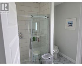 A white bathroom with a glass shower door and a toilet.