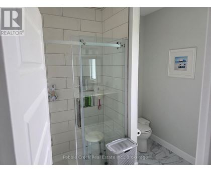 A white bathroom with a glass shower door and a toilet.