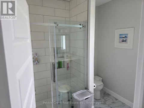 A white bathroom with a glass shower door and a toilet.