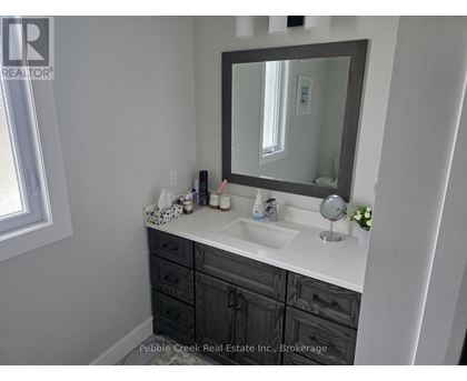 A bathroom with a sink, mirror, and a window.