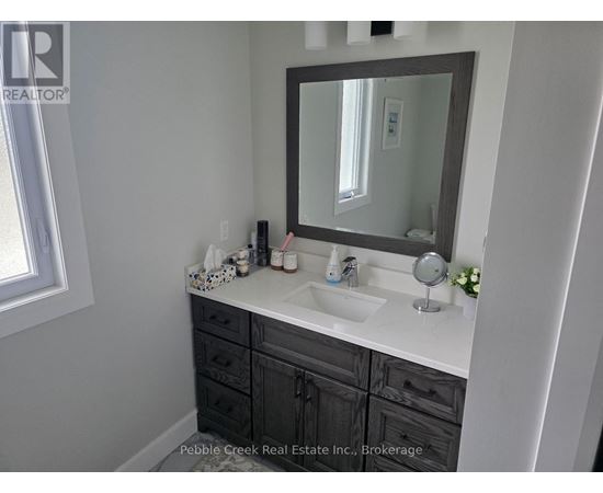 A bathroom with a sink, mirror, and a window.