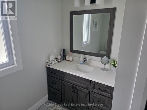 A bathroom with a sink, mirror, and a window.