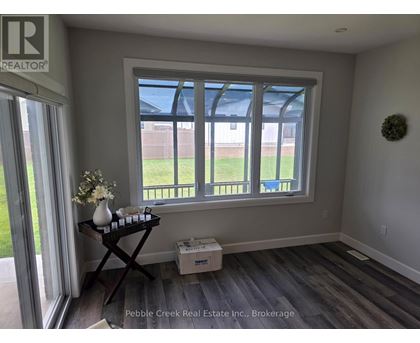 A room with a window and a table with a vase of flowers on it.