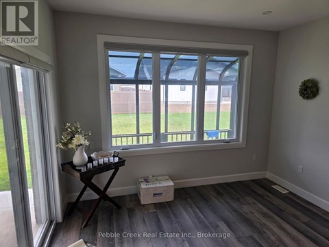 A room with a window and a table with a vase of flowers on it.