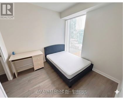A bedroom with a bed, desk, and window.