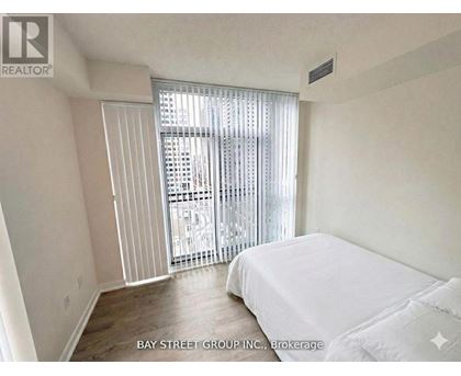 A bedroom with a large bed and a sliding glass door leading to a balcony.