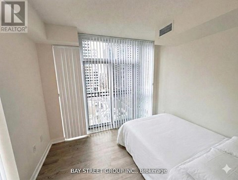 A bedroom with a large bed and a sliding glass door leading to a balcony.