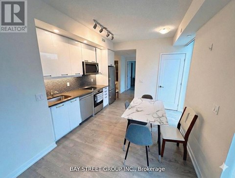 A kitchen with white cabinets and a counter with a chair and a person sitting at it.