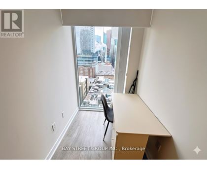 A room with a desk and a chair with a window that has a view of the city.